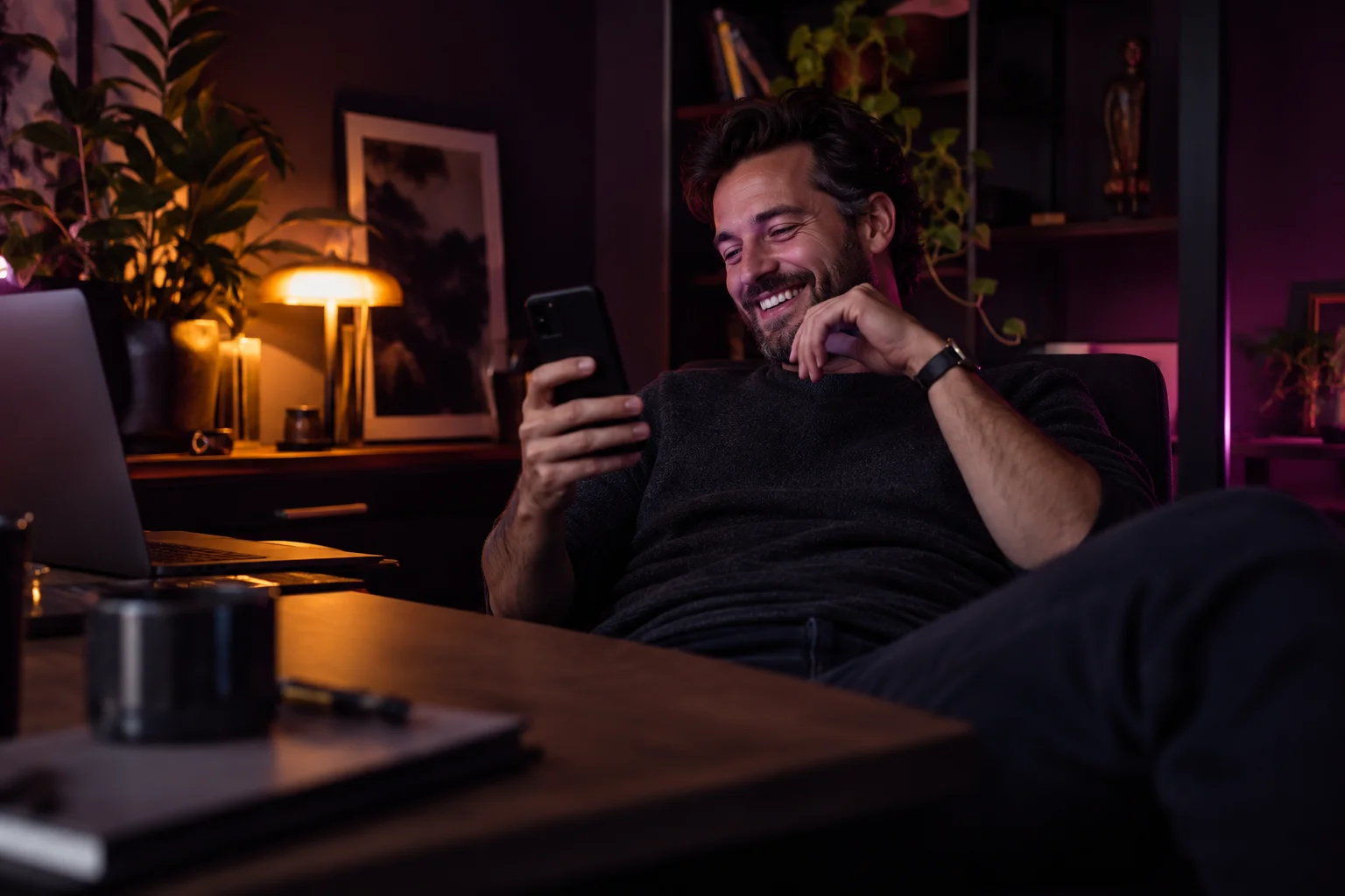 Man leaning back and laughing while reading a message on his phone